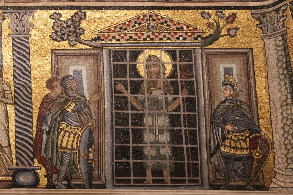 A mosaic of a bearded figure with a halo behind bars, flanked by armed men.