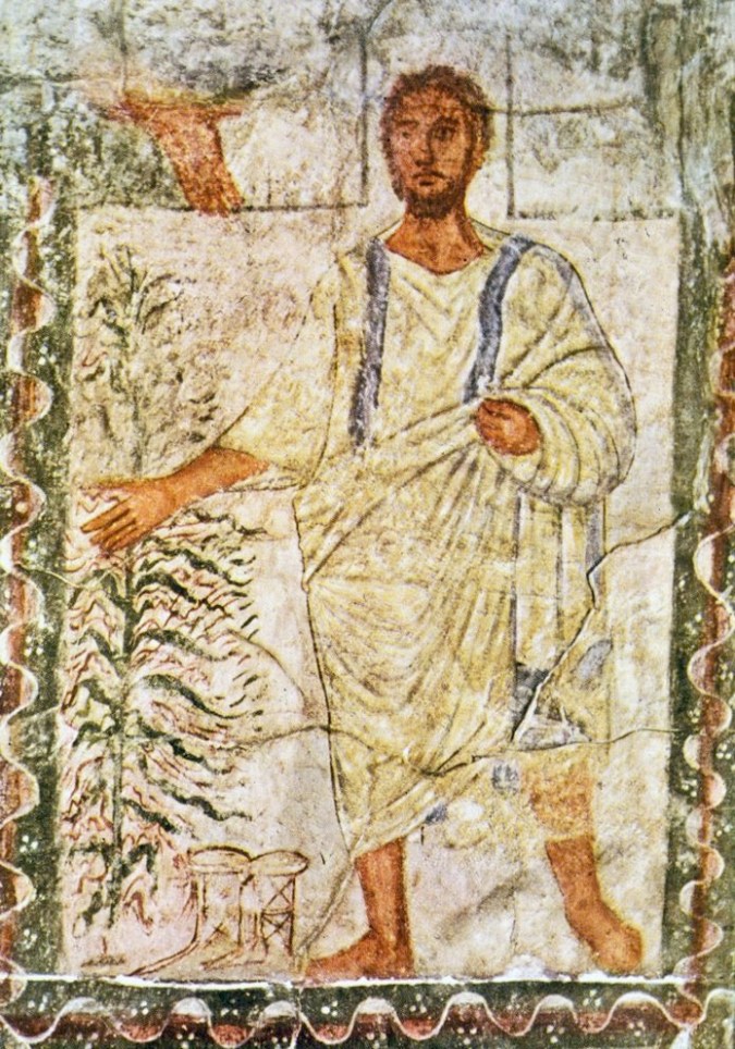 A male figure standing next to a bush.